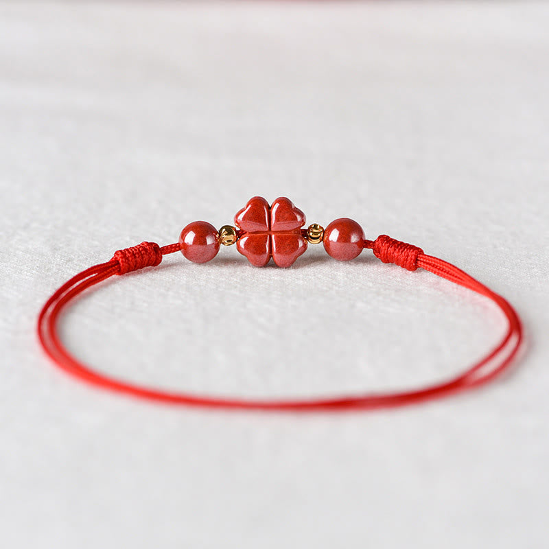 Rotes Armband Zinnober Kleeblatt mit goldenen Perlen auf weißem Hintergrund Nahaufnahme