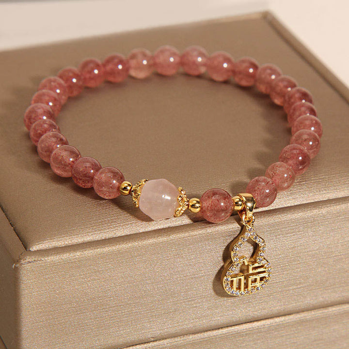 Armband Erdbeerquarz Fu-Zeichen rosa Perlen goldene Verzierungen elegant.