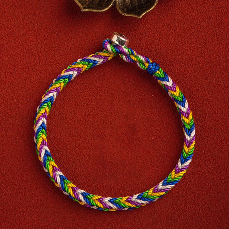 Buntes geflochtenes Armband mit Glück Charm auf rotem Hintergrund.
