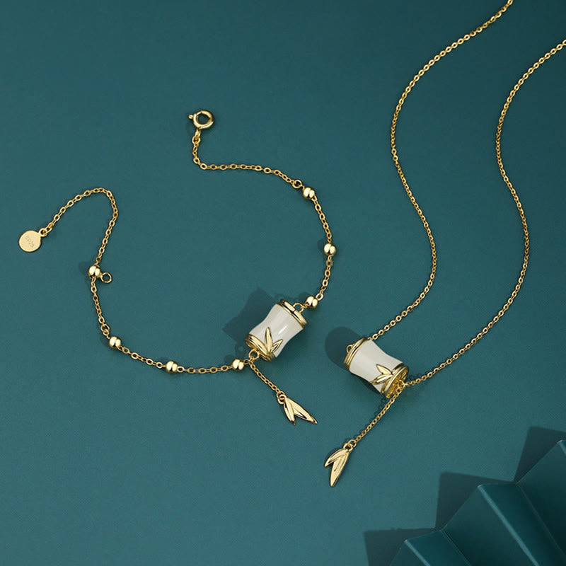 Goldene Armbänder mit weißer Jade und Bambus-Anhängern auf Türkis.