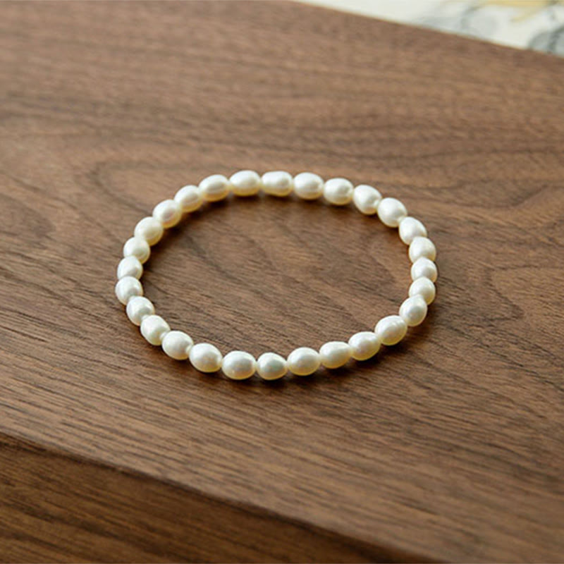 Armband Perle – Heilung weiße Perlen elastisch Holzuntergrund natürlich elegant
