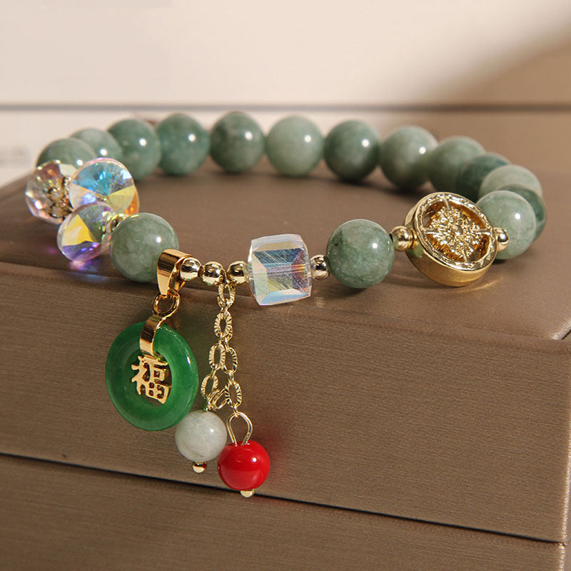 Grünes Jade Armband mit Gold-Elementen und Anhängern elegant präsentiert.