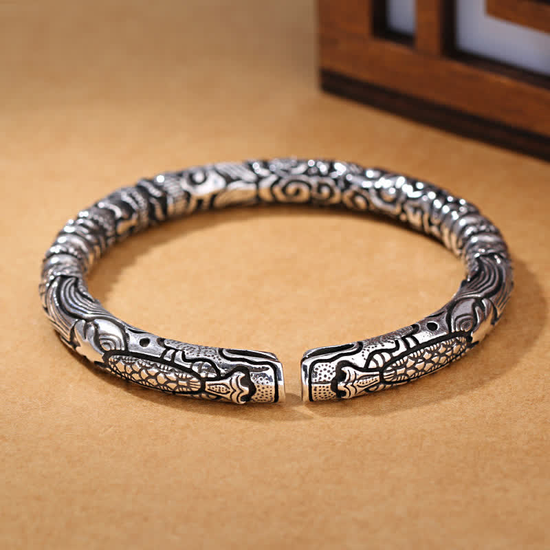 Silbernes Drachen-Armband mit Glück Symbol auf Holztisch.