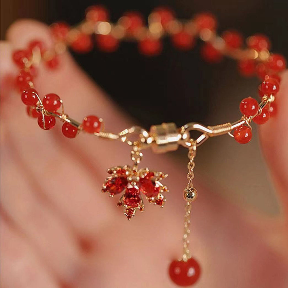 Rotes Ahornblatt Armband mit goldenen Perlen elegant getragen
