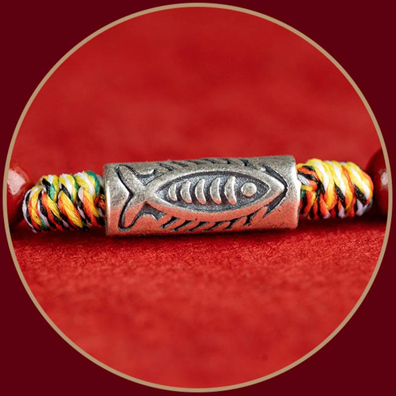 Armband mit Koi Fisch Anhänger und bunten Seilen auf rotem Hintergrund.