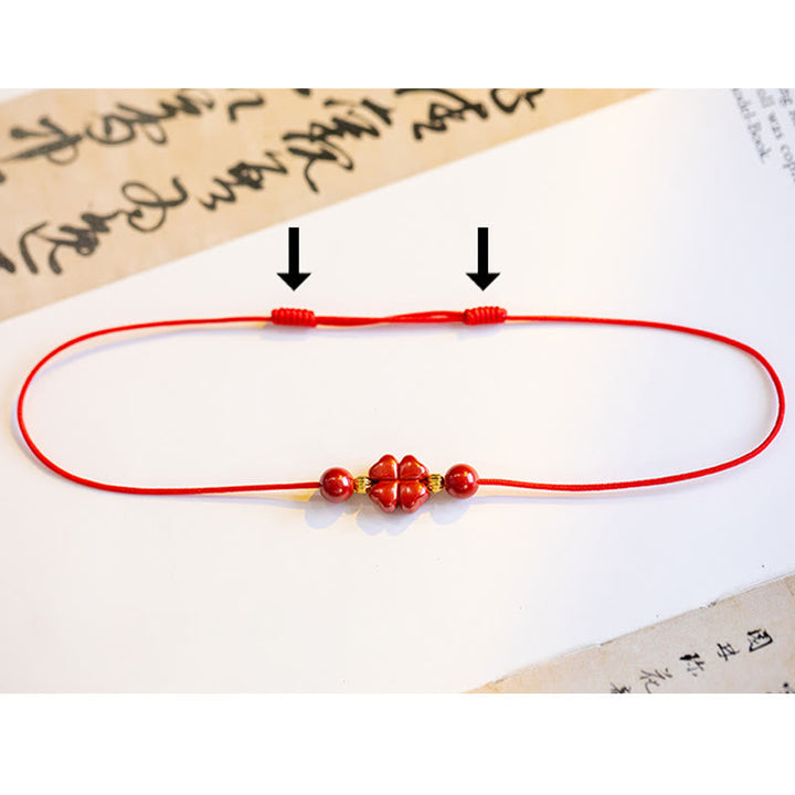 Rotes Armband Zinnober Kleeblatt auf Papier mit Schriftzeichen, elastisch.
