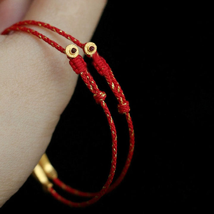 Rotes Armband mit goldenen Perlen am Handgelenk, Glück Wohlstand Segen