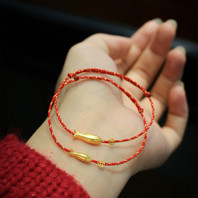 Rotes Armband mit Goldfisch-Anhänger am Handgelenk getragen Glück Wohlstand