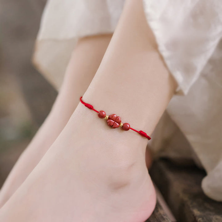 Rotes Armband Zinnober Kleeblatt am Handgelenk getragen, eleganter Naturstein