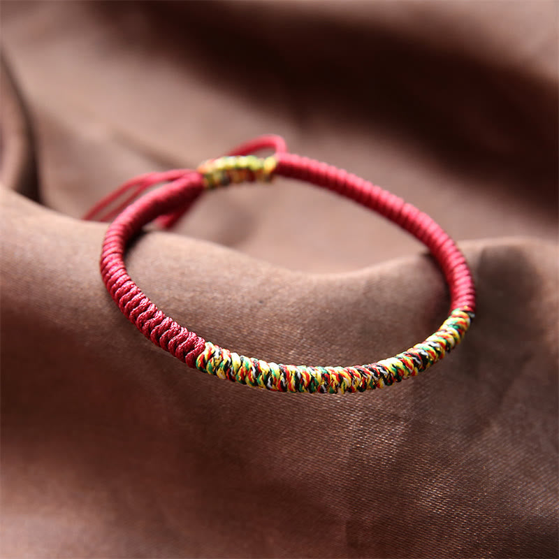 Rotes Armband – Glück & Stärke mit bunten Webdetails am Handgelenk