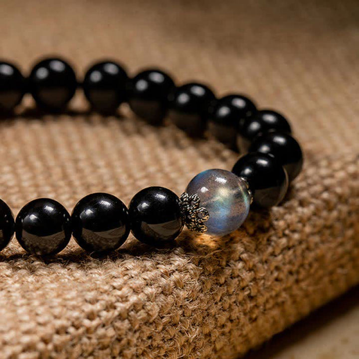 Schwarzes Obsidian Armband mit silbernem Verschluss auf Leinenstoff.