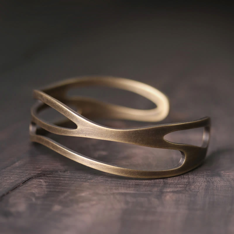 Kupfer Armband mit offener Spaltform auf grauem Holz Hintergrund.