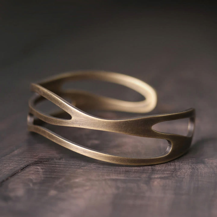 Kupfer Armband mit offener Spaltform auf grauem Holz Hintergrund.