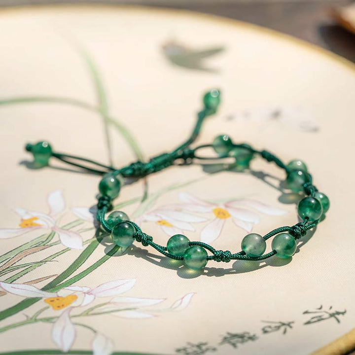 Grünes Achat Armband auf bedrucktem Papier mit Blumenmotiven getragen