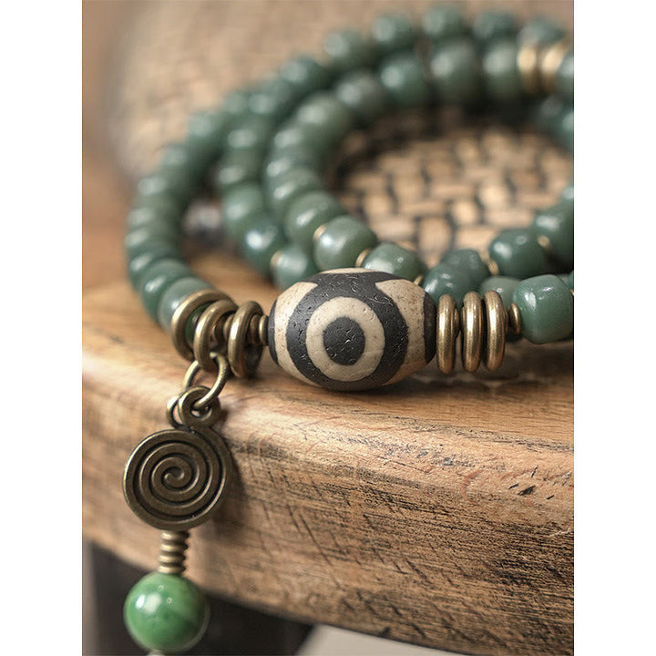 Grünes Bodhi Armband mit bronzenen Perlen und Spiralanhänger elegant.
