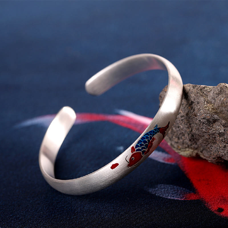 Silbernes Armband mit Koi Fisch Design auf Stein elegant präsentiert.