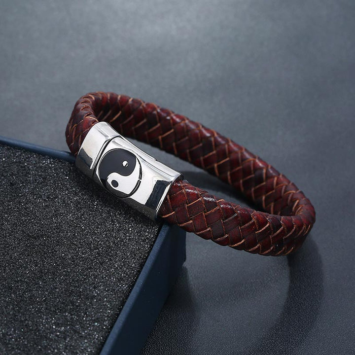 Rotes Lederarmband mit Yin Yang Verschluss auf grauem Stein Nahaufnahme