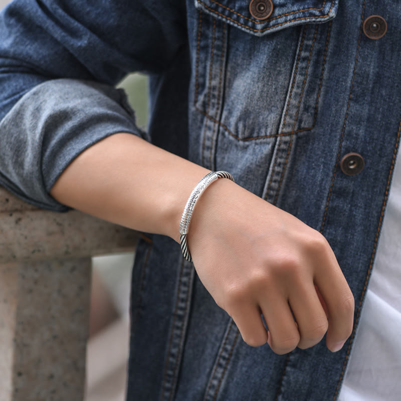 Silberfarbenes Armband Om Mani Padme Hum Herzsutra am Handgelenk getragen Jeansjacke