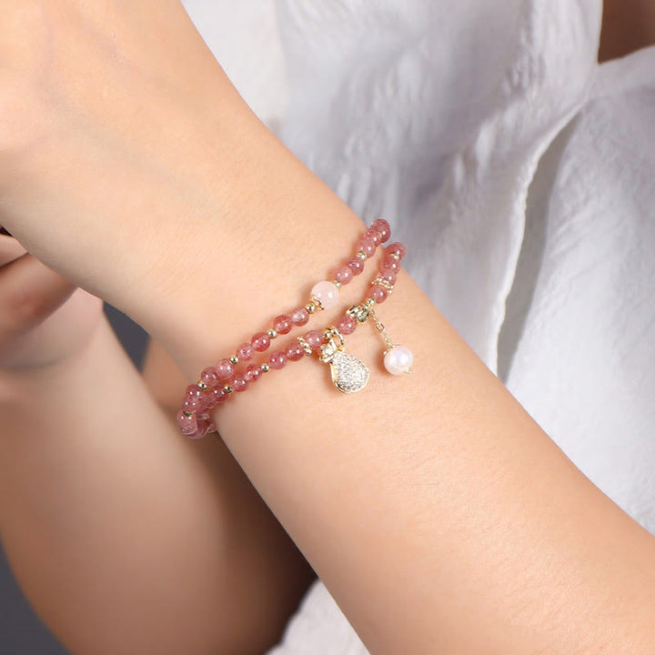 Armband Erdbeerquarz mit Perlenanhängern elegant am Handgelenk getragen