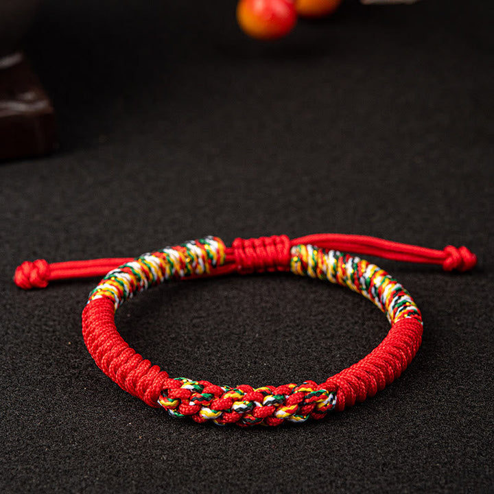 Rotes Mala Armband mit bunten Fäden auf schwarzem Untergrund, Nahaufnahme