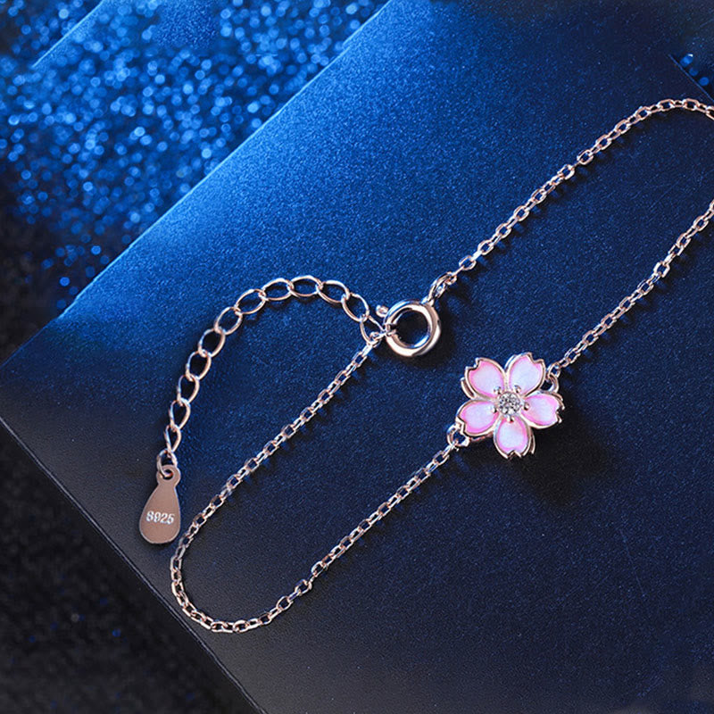 Silberarmband 925 mit rosa Blütenanhänger auf blauem Hintergrund elegant.
