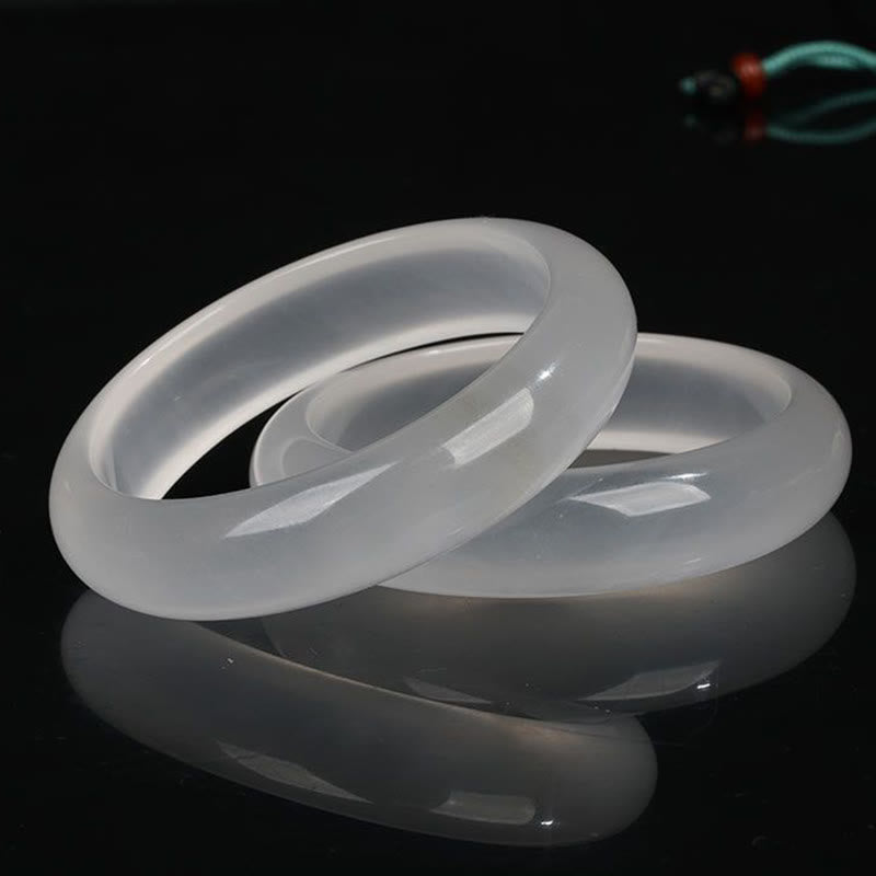 Zwei transluzente Jade Armbänder auf schwarzem Hintergrund elegant angeordnet.