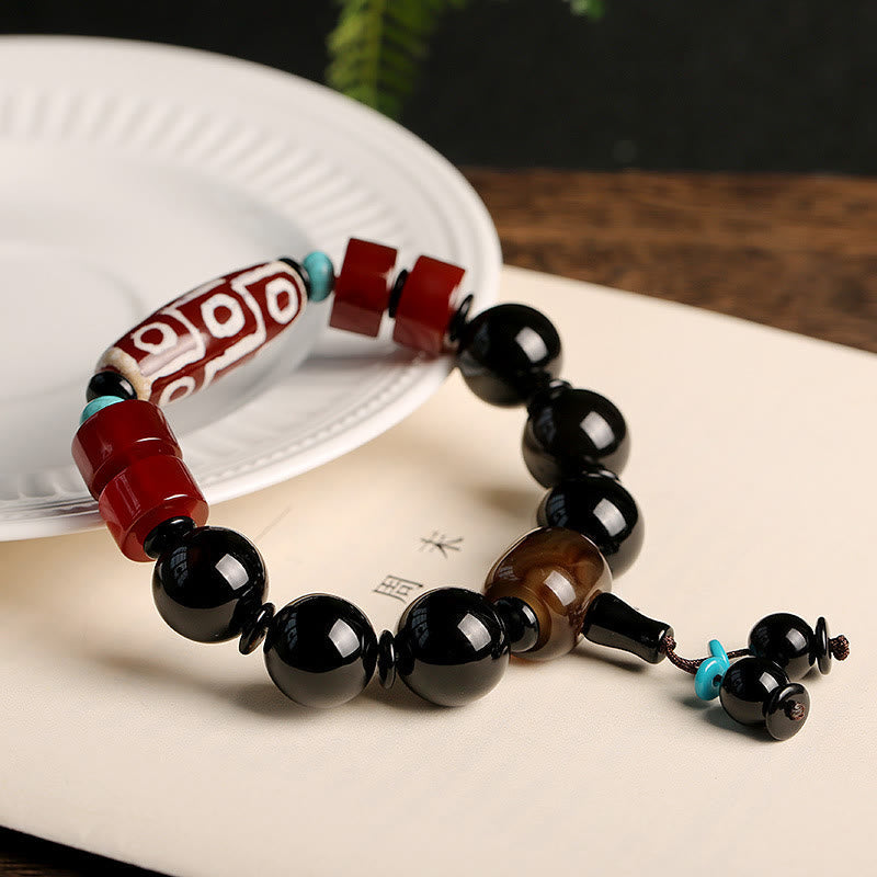 Armband Schwarzer Onyx mit roten Perlen und türkisen Akzenten elegant arrangiert.