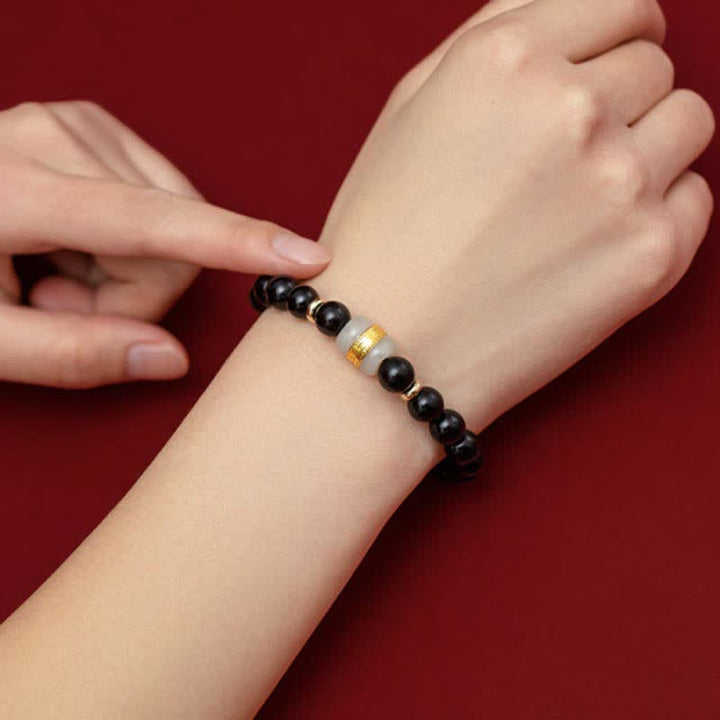 Schwarzes Obsidian Armband mit goldener Perle am Handgelenk getragen