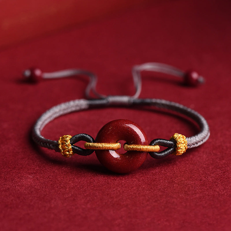 Armband Zinnober – Frieden & Segen Energie mit goldenem Akzent auf rotem Untergrund.