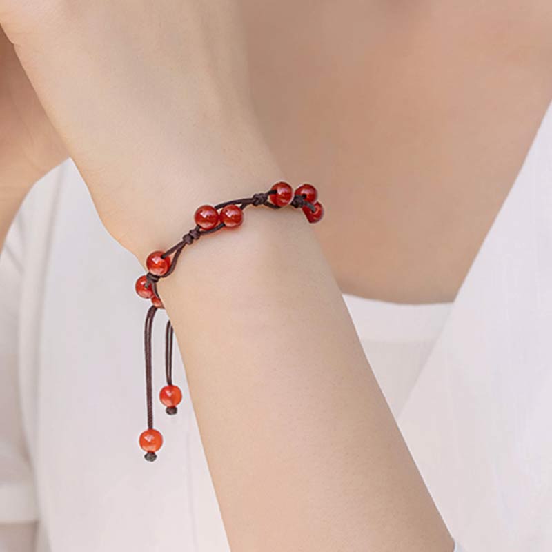 Armband Roter Achat Zinnober am Handgelenk mit braunem Seidenband getragen