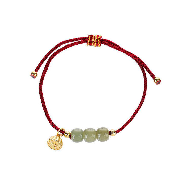 Armband Jade Lotus mit roten Kordeln und goldenen Perlen Handgelenk.