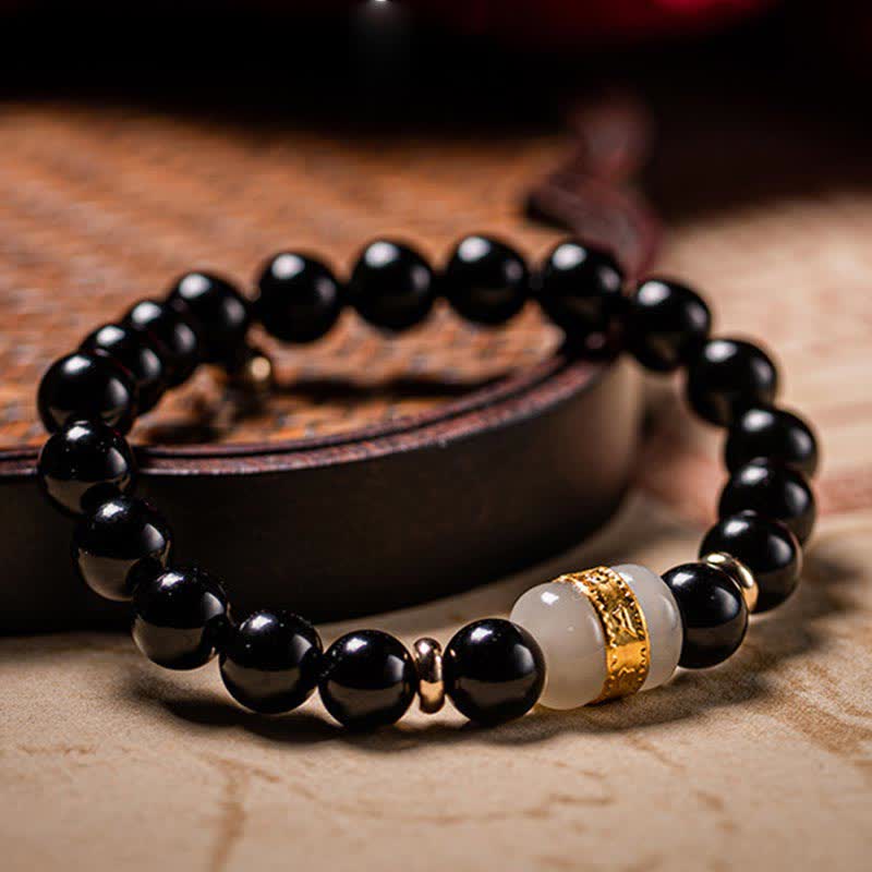Armband schwarzer Obsidian mit weißer Jade und goldener Om-Verzierung elegant.