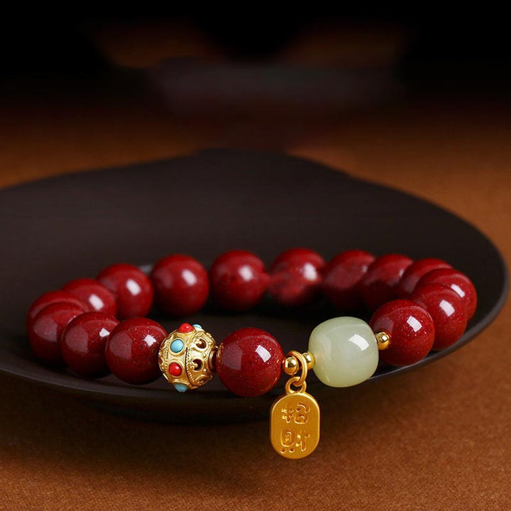 Rotes Armband mit Zinnober-Perlen auf schwarzer Keramikschale, Detailaufnahme.