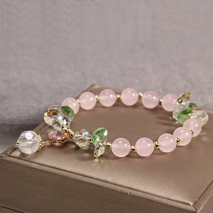 Roséquarz Kristall Armband mit grünen Perlen elegant präsentiert.