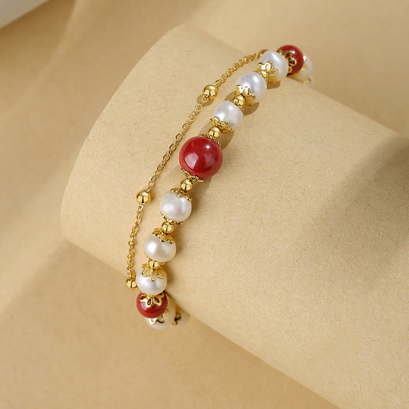 Elegantes Armband mit roten Zinnober-Perlen und weißen Perlen, goldfarben.
