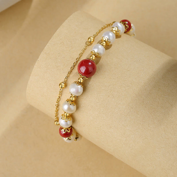 Elegantes Armband mit roten Zinnober-Perlen und weißen Perlen, goldfarben.