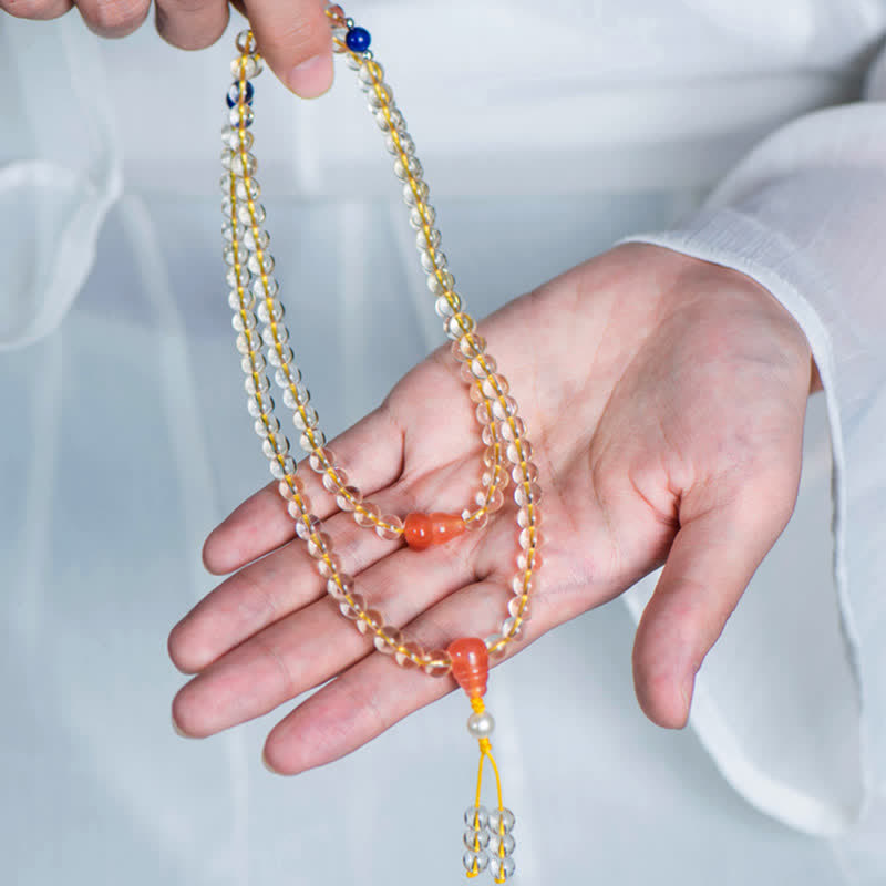 Mala Armband mit goldenen Perlen und roten Achatsteinen getragen.