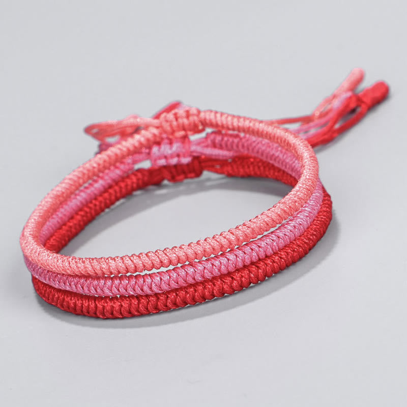Tibetisches geflochtenes Armband in Rosa und Rot Tönen, elastisch.