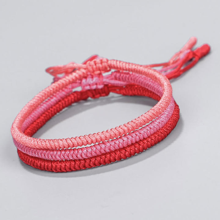 Tibetisches geflochtenes Armband in Rosa und Rot Tönen, elastisch.