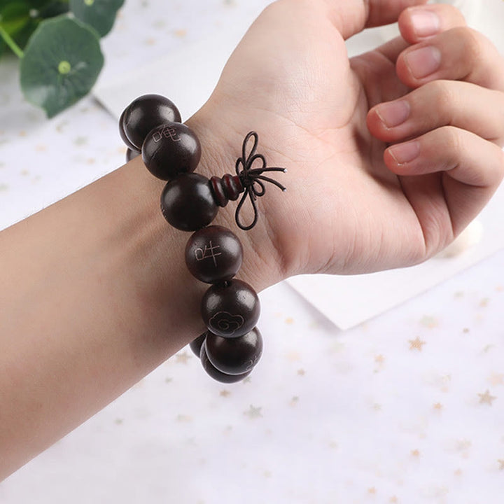 Schwarzes Perlenarmband mit Om Symbol am Handgelenk getragen elegant