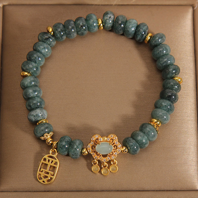 Jade Armband mit goldenen Verzierungen auf beigem Hintergrund.