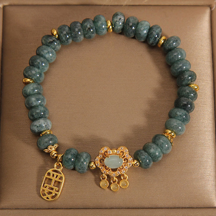 Jade Armband mit goldenen Verzierungen auf beigem Hintergrund.