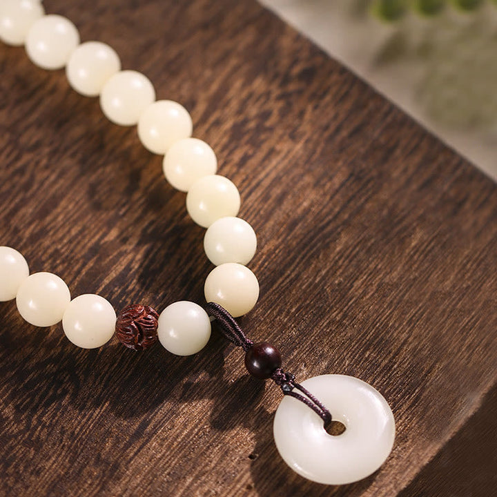Weißes Bodhi Lotus Armband mit Sandelholz Perlen auf Holz.