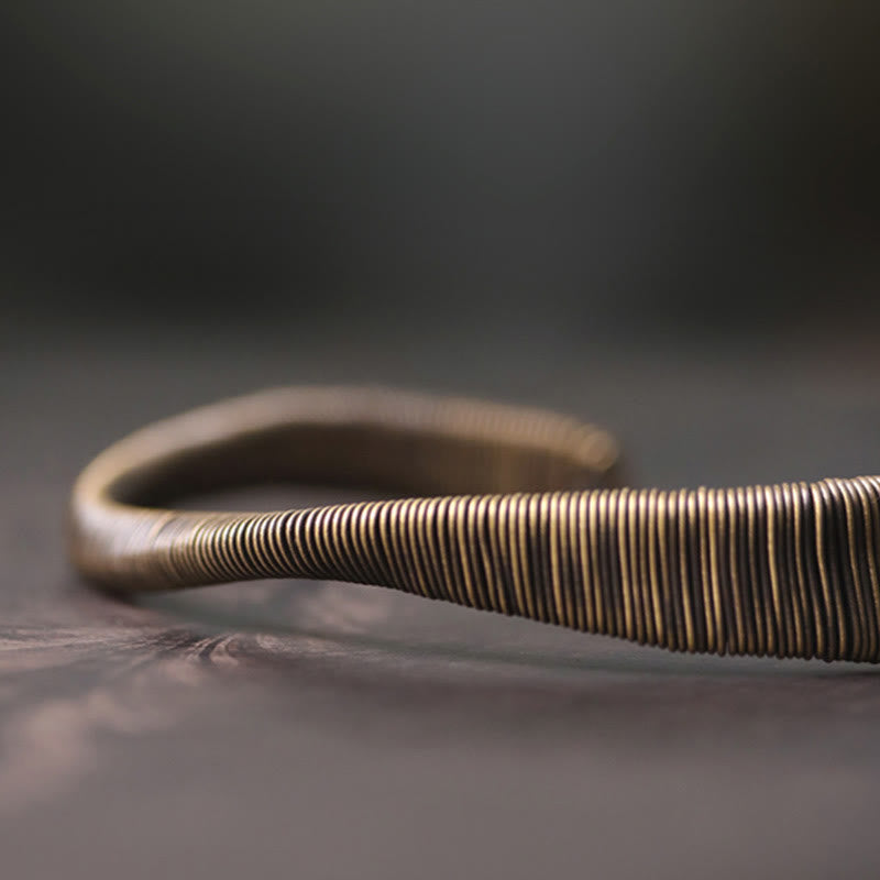 Kupfer Armband mit Spiralmuster auf grauem Hintergrund elegant.