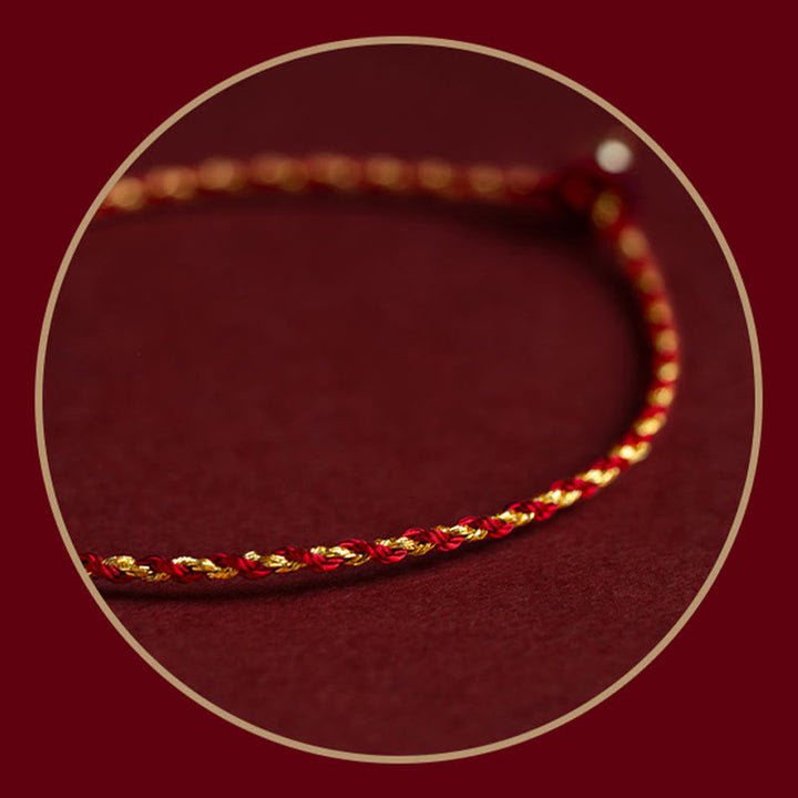 Rotes geflochtenes Armband mit goldenen Akzenten auf Burgunderhintergrund.