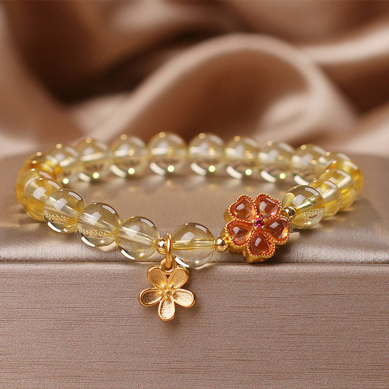Armband Citrin mit goldenen Blütenanhängern elegant präsentiert
