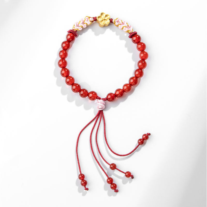 Rotes Achat Armband mit goldener Blüte und Quasten elegant präsentiert