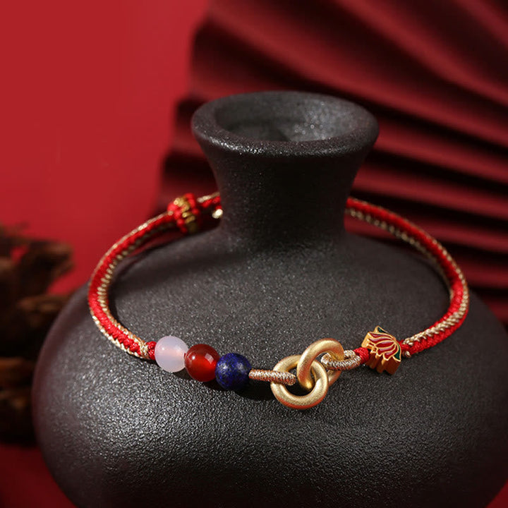 Rotes Armband mit Lotusanhänger und bunten Perlen elegant präsentiert.