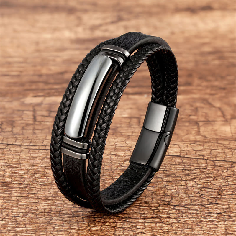 Schwarzes geflochtenes Lederarmband mit Edelstahlverschluss auf Holz