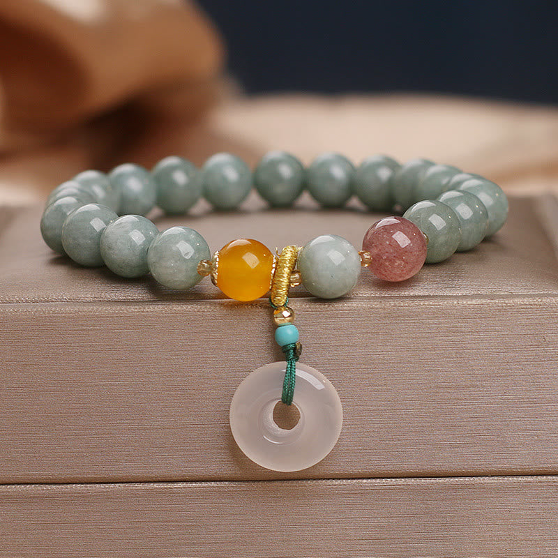 Jade Armband Erdbeerquarz mit Donut Anhänger auf Holz.